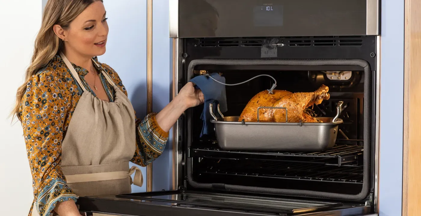 lady taking turkey out of oven